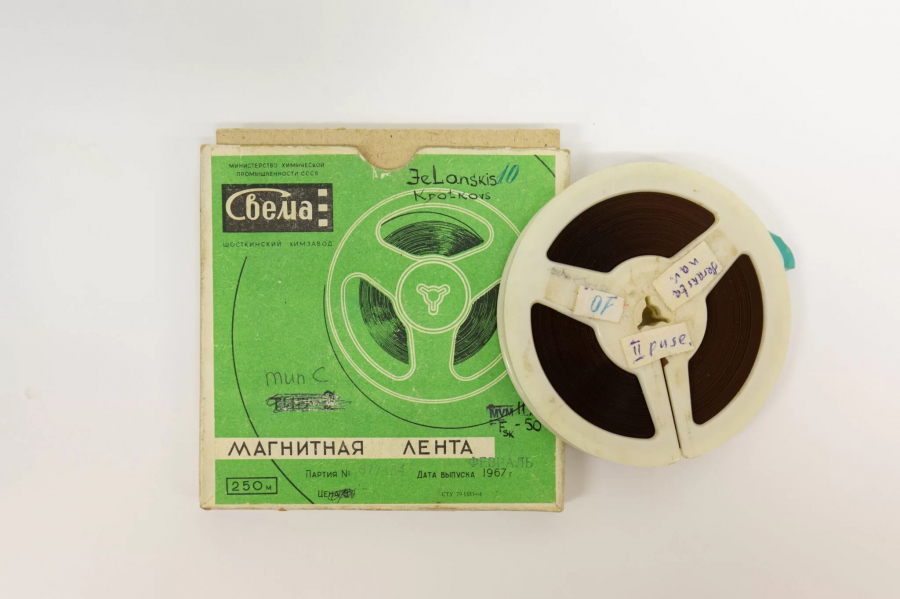 Аудиокассета из коллекции МИМ рядом с зеленой упаковочной коробкой.