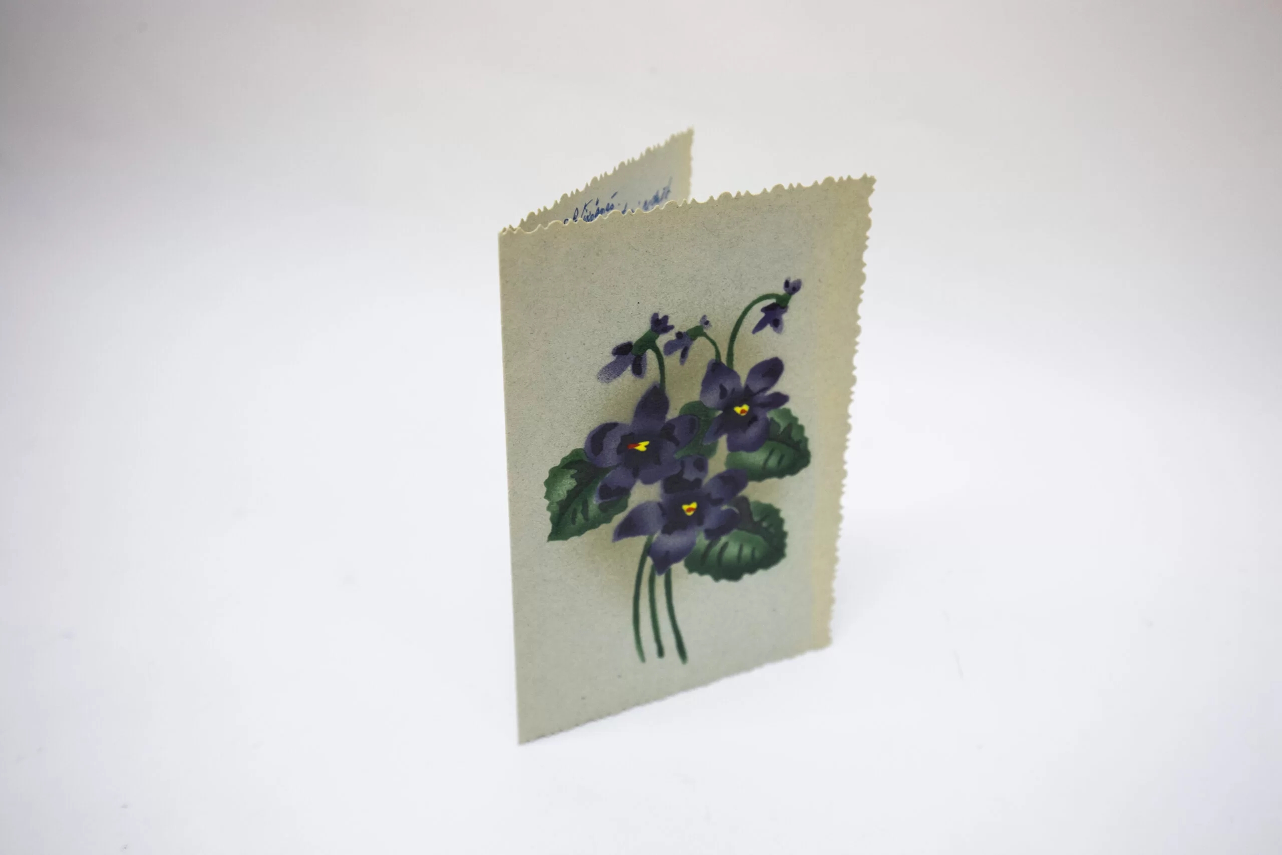 Card with decorative, rough edges. Above it is a drawing with a bouquet of purple flowers.