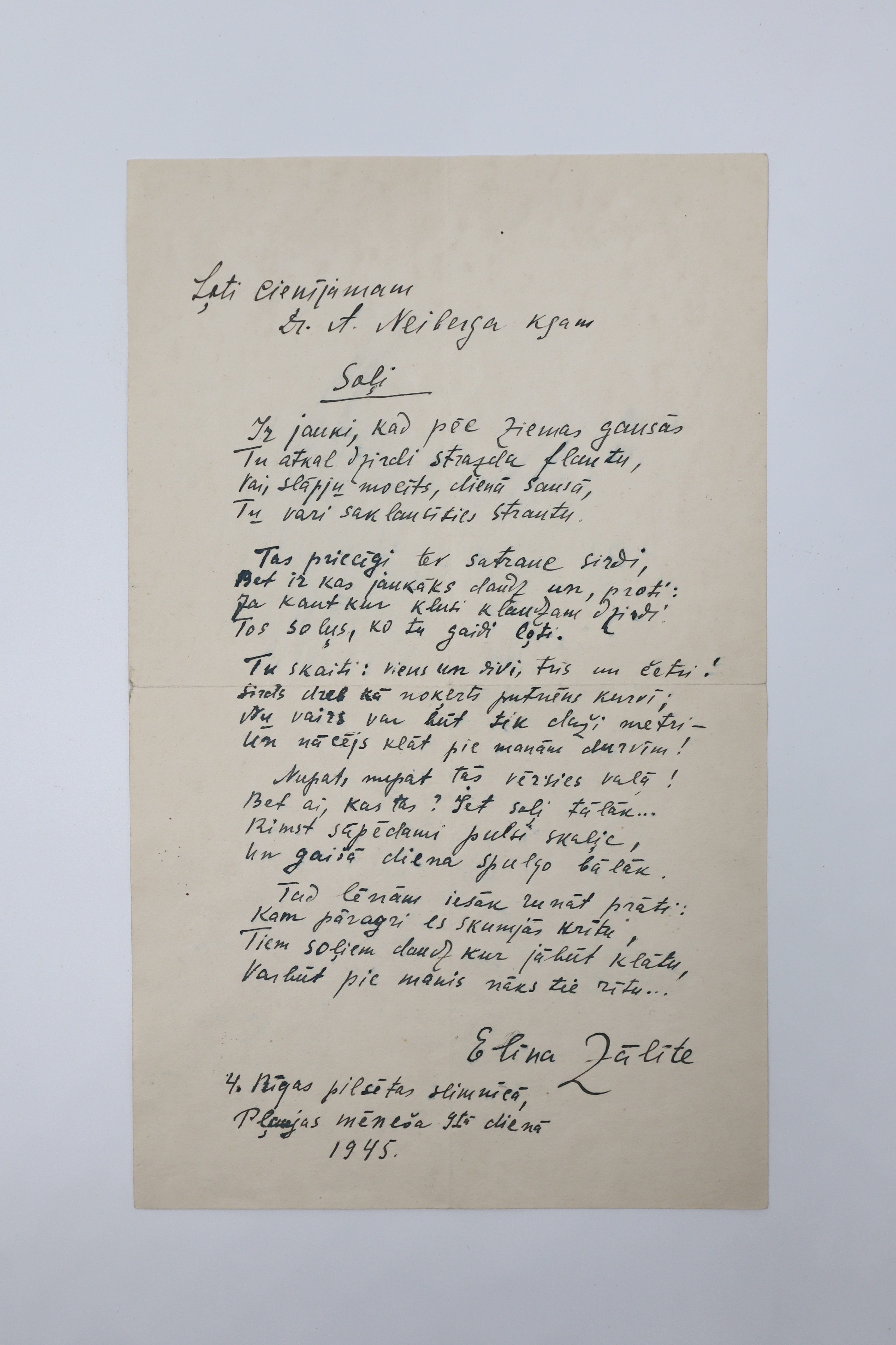 Dzeltenīga lapa, uz kuras rakstīts dzejolis melnā krāsā. Apakšā redzams Elīnas Zālītes paraksts un adrese, gads.